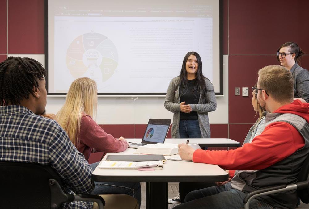 Student speaking from front of classroom to other students